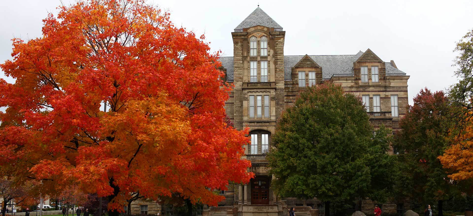 Adelbert Hall in the fall with a tree of read leaves next to it