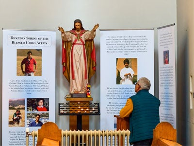 Photo of a person looking at the shrine for Saint Carlo Acutis