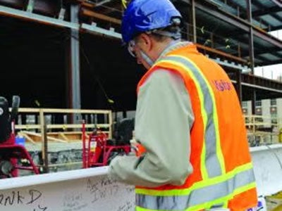 A construction worker signs a beam before the ISEB topping off ceremony.