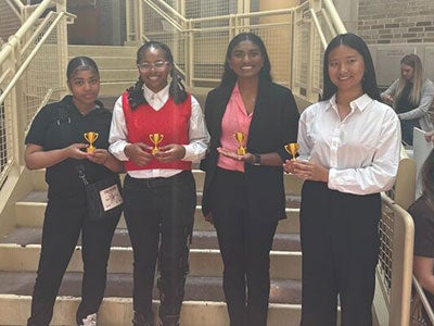 Four high school students being awarded 3D-printed trophies for  best presentation