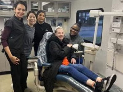 Dental students pictured with a patient in the chair in the van.