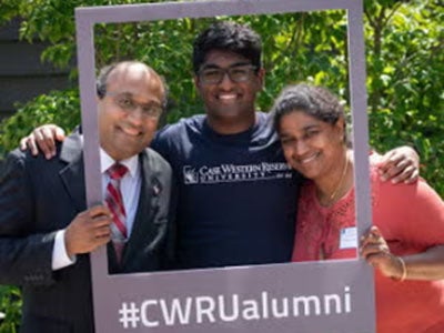A family poses inside an alumni photo frame