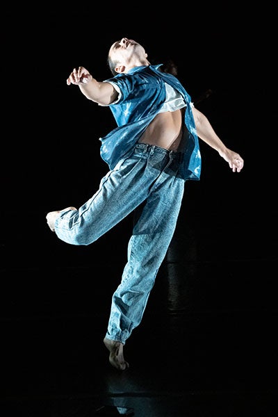 Chris Bell dancing on a dark stage