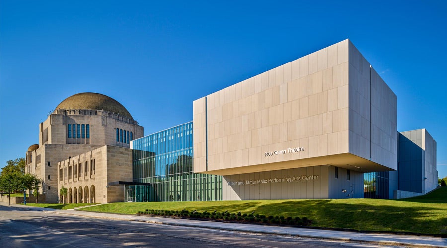 Modern performing arts center with a mix of glass and stone architecture, featuring a large domed building