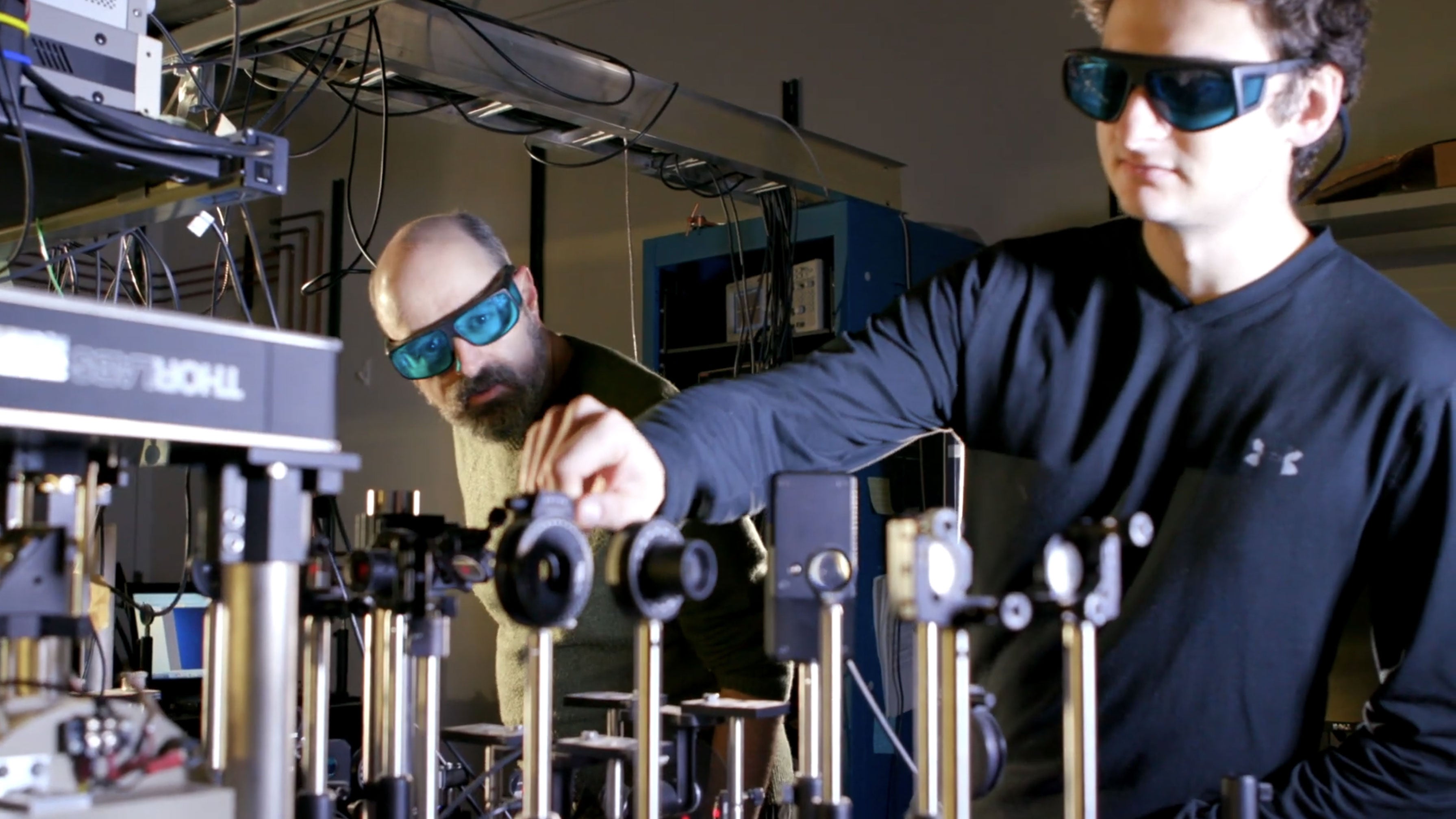 Photo of Jesse Berezovsky looking over a student researcher's shoulders as they work in the lab