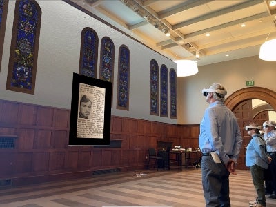 Two people with virtual headsets looking at a virtual memorial display