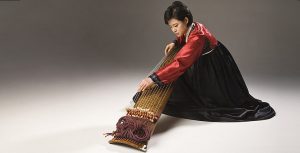 Photo of Ji Aeri playing the kayagum against white background