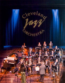 A large assemblage of jazz musicians playing on stage