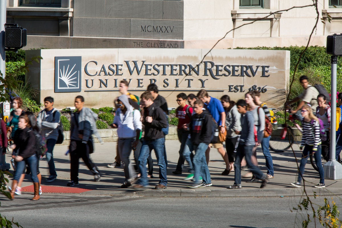 CWRU students walk in front of sign on Adelbert Road