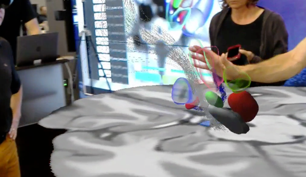 researchers wearing holographic headsets  at a table view a 3D image of a human brain