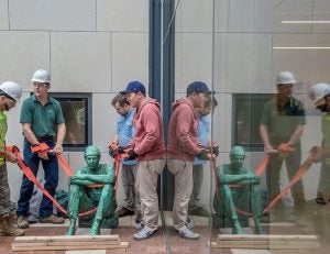 Workers install the homeless sculpture outside the Mandel School at Case Western Reserve University.
