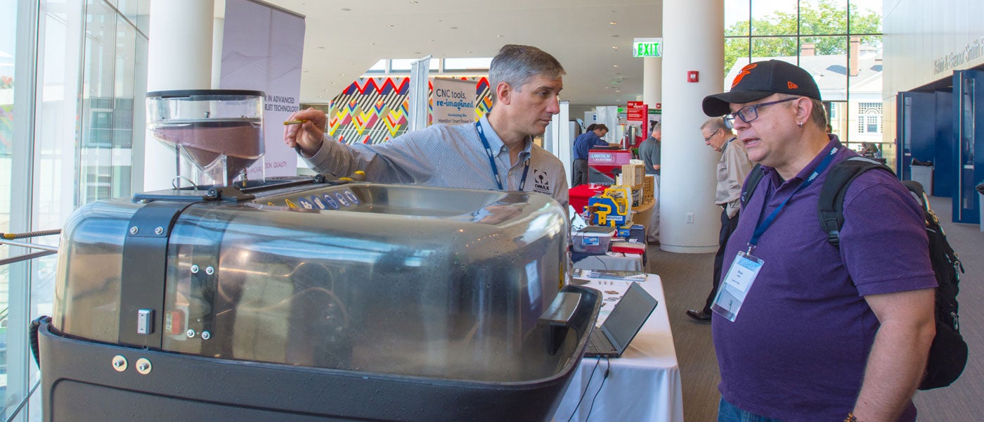 Photo of a conference vendor demonstrating a waterjet cutter.