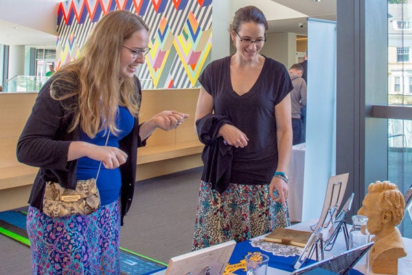 Photo of to conference volunteers discussing 3-D-printed items.