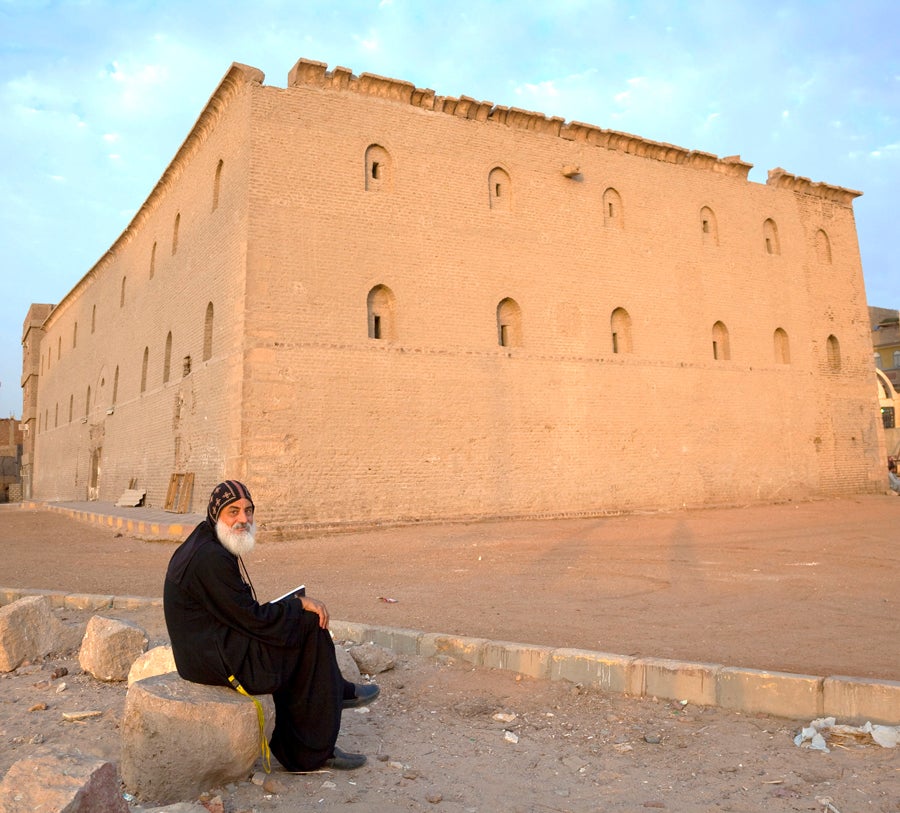 A priest sites outside of a church.