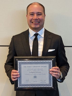 Case Western Reserve University nursing faculty member Nathanial Schreiner holds a framed Diekhoff Award certificate