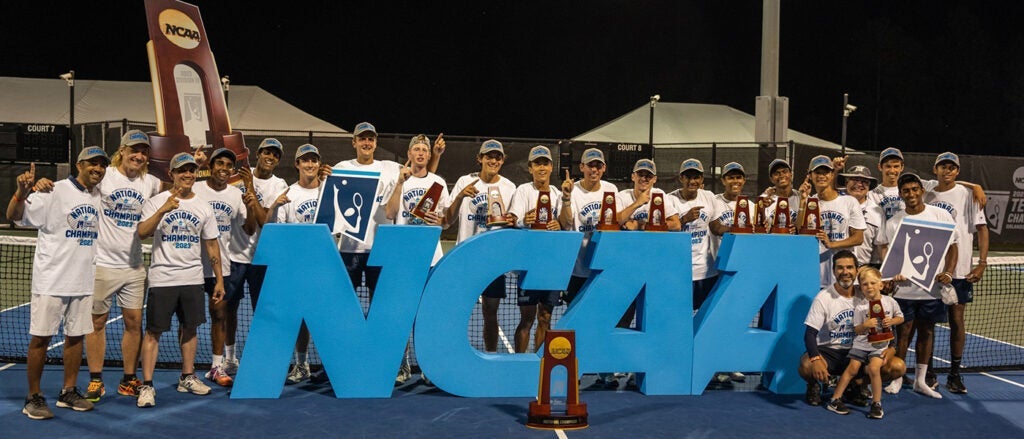 The CWRU men's tennis team poses by a large NCAA sign after winning their first national championship
