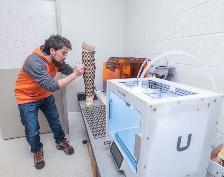 Photo of a research in Ozan Akkus's lab working on a material wrapped around a leg model