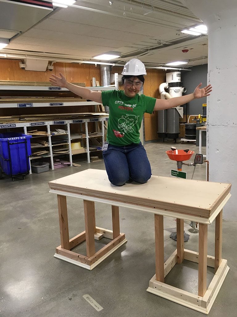 Alice Li kneels on desk she built at Sears think[box]