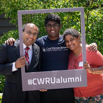 Photo of a family of three posing for a photo with a frame that says "#CWRUalumni"