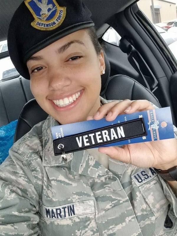 Photo of Chiane Martin in uniform and holding a tag that says "veteran"