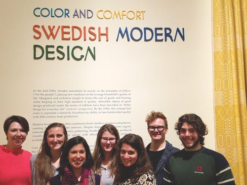 students posing in front of museum exhibition they created