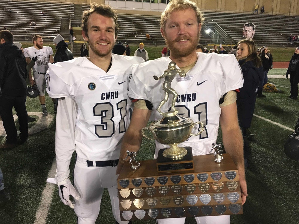 Photo of Cooper and Hunter Tulloch in their football uniforms holding a trophy