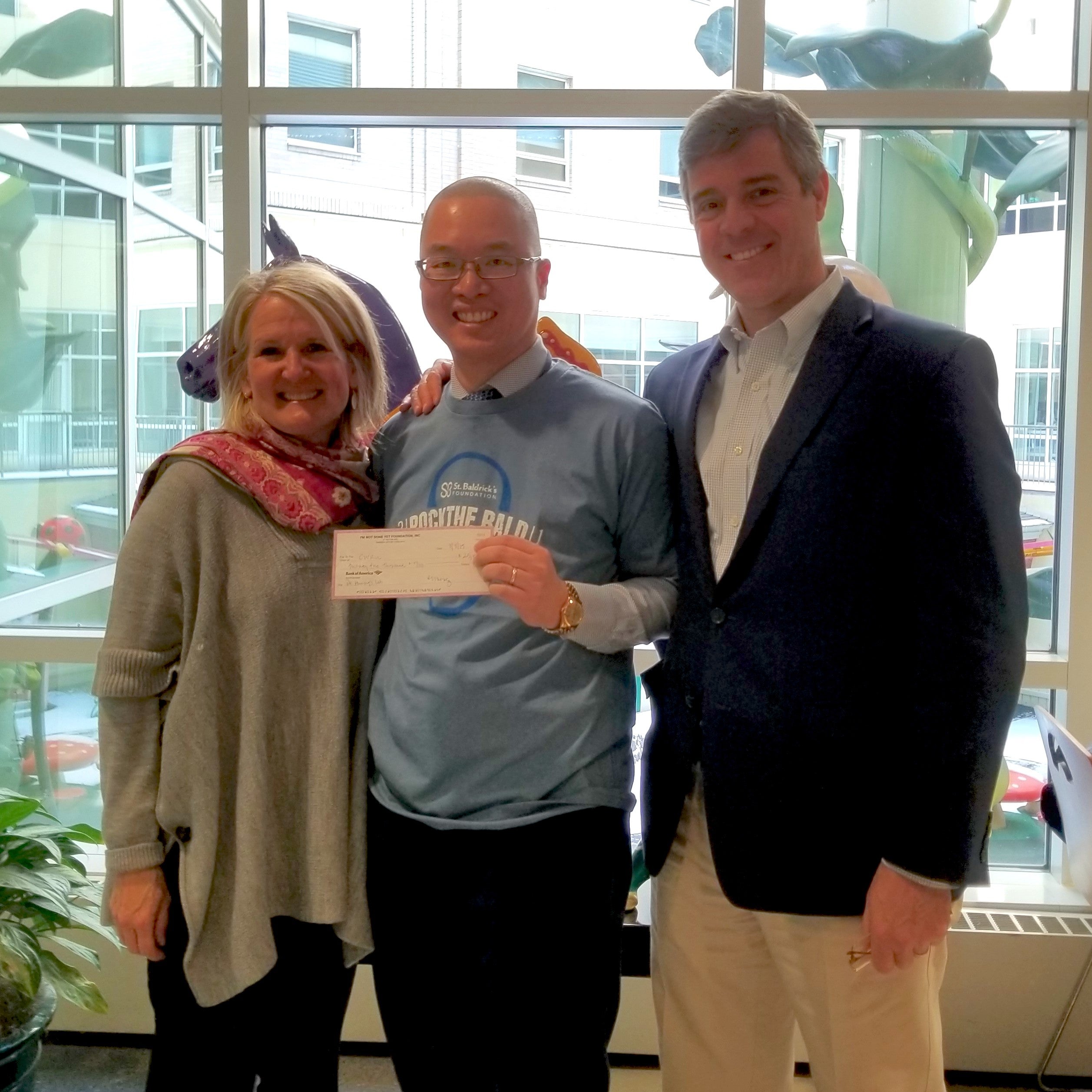 A photo of Liz Mendes, Alex Huang and Peter Mendes with Alex holding a check