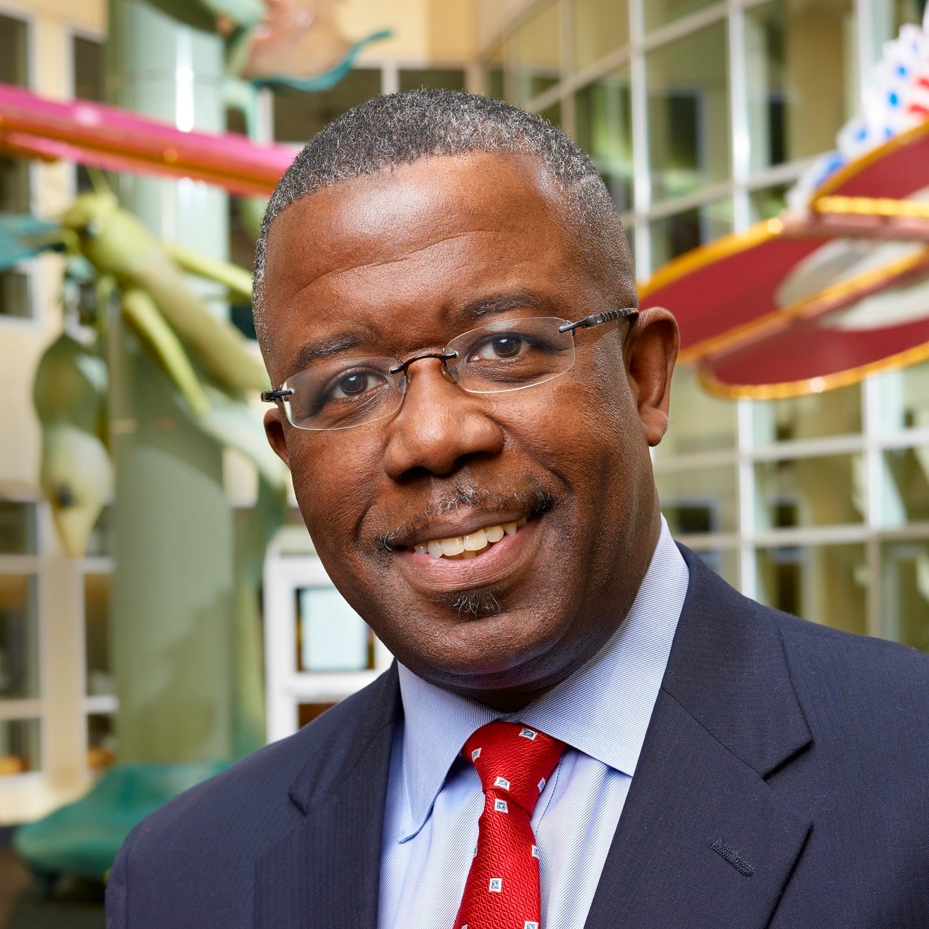 Portrait of Dr. Edward Barksdale in a navy suit jacket with red tie, smiling