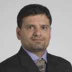 Portrait of Kailash Gulshan, man with dark hair looking at camera wearing a dark suit coat, blue dress shirt and a tie. 