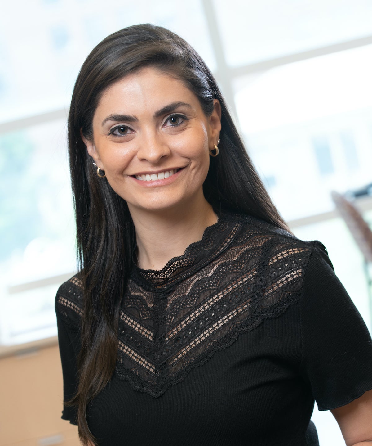 Portrait of Yami Huerta standing in front of window in lab wearing a black short sleeved shirt