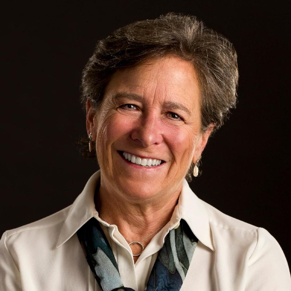 Portrait of Eileen Saffran wearing white blouse and scarf smiling into camera
