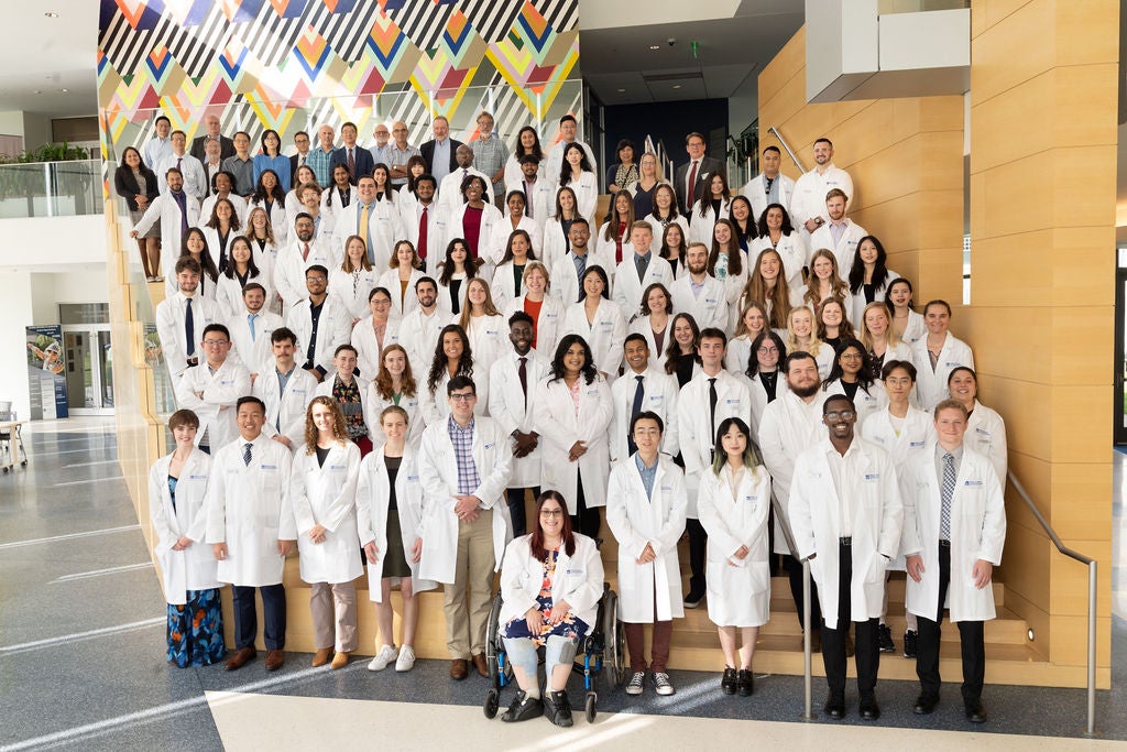 Group of students gathered together wearing white lab coats