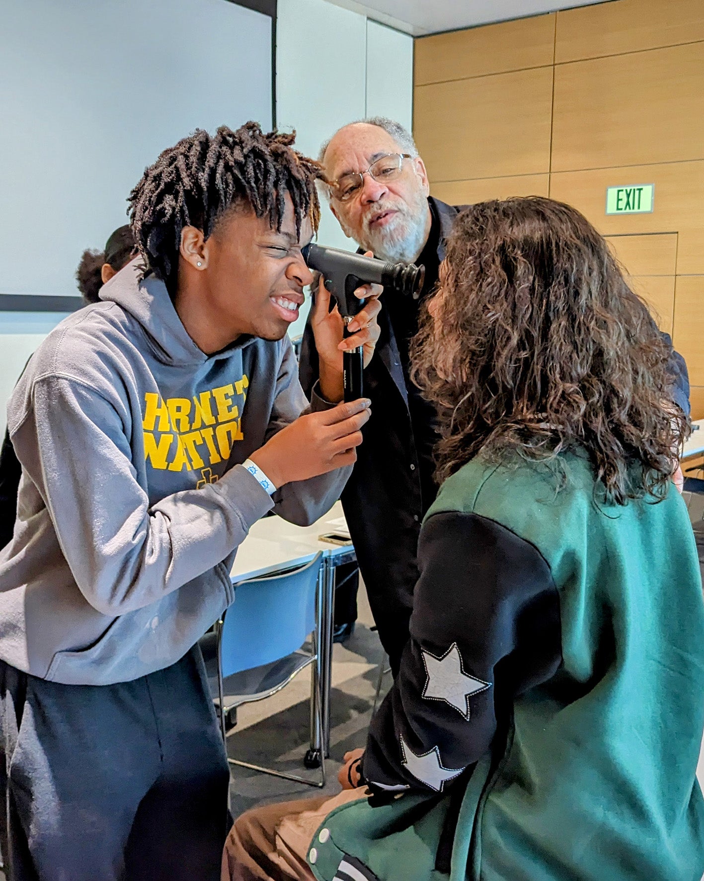 high school student examining another student's eyes