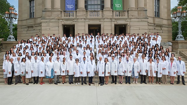 M1 students outside Severance Music Center wearing white coats