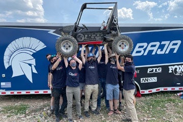 Photo of CWRU Motorsports team hoisting vehicle up in the air