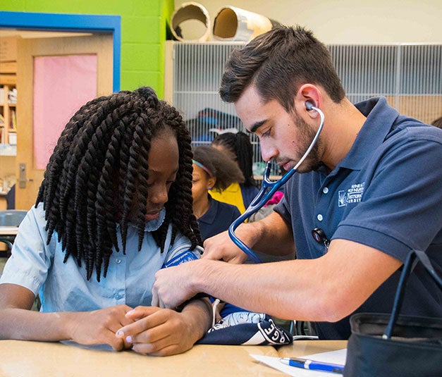 Photo of a CWRU FPB student checking a child's blood pressure. 