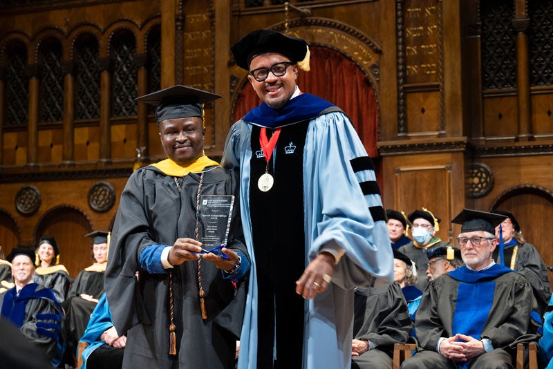 Ayowole Samuel Ajiboye and Dexter Voisin smile on stage at commencement