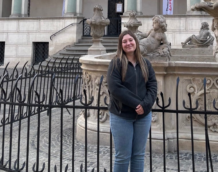Shyanne Urban stands in front of an iron gate in Poland