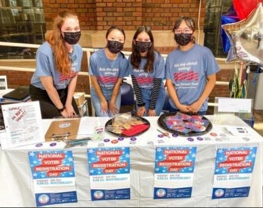 Photo of Nguyen, Wicker and Jackson working at a voter registration table.