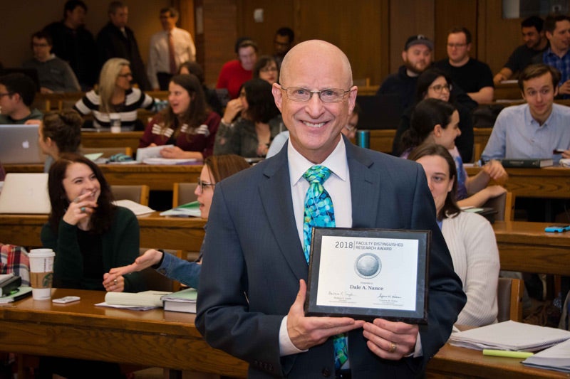 Photo of Dale Nance holding Faculty Distinguished Research Award plaque