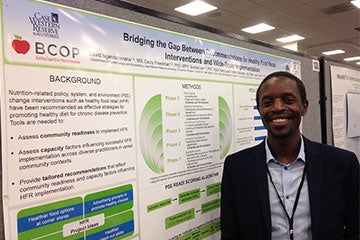 David Ngendahimana poses in front of his poster presentation