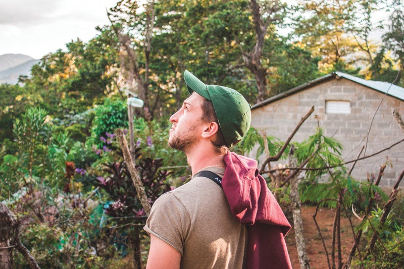 Photo of CWRU student Michael Douglass looking toward the sky while surrounded by trees in the Dominican Republic