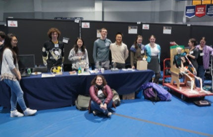 Photo of Gabrielle Parkin posing for a photo with students in her medieval robots course during the Celebration of Student Writing & Research