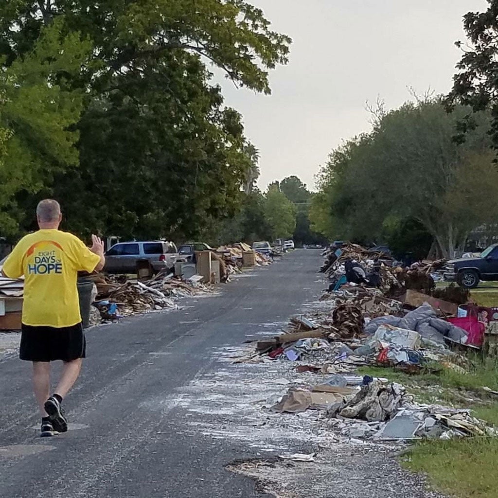 Photo of Wayne Hawthorne walking down a road affected by a natural disaster with debris on the road