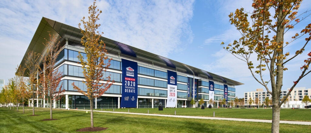 Photo of the Health Education Campus with debate signage against a blue sky