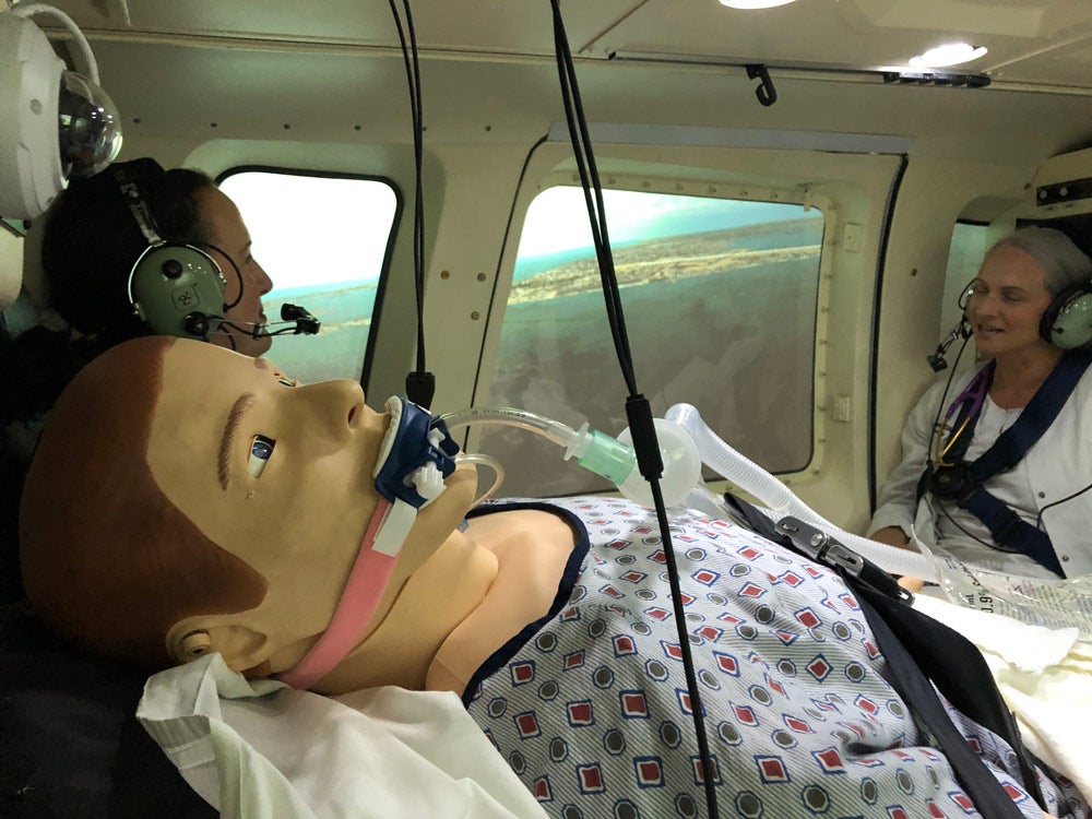 Photo of a dummy being used as a patient in a simulated emergency flight with two nurses