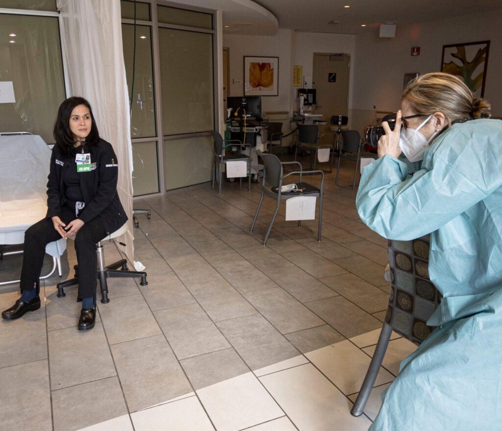 Photo of Janine Llamzon posing for a photo in a hospital setting as a photographer takes a picture