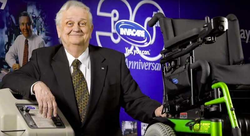 J.B. Richey next to Invacare sign and wheelchair