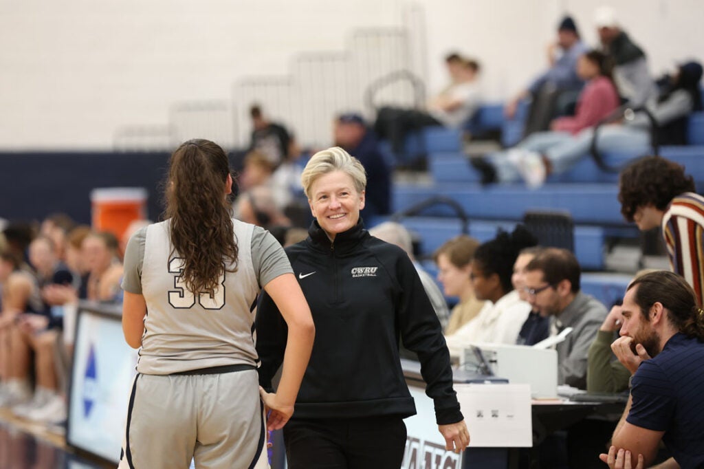 Photo of CWRU women's basketball coach Jennifer Reimer on the sidelines with a player during a game