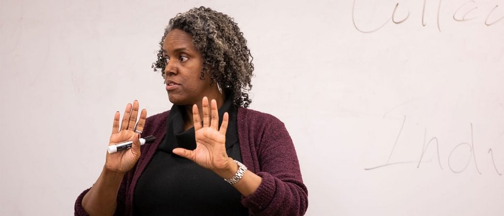 Photo of Joy Bostic teaching with a dry erase board behind her